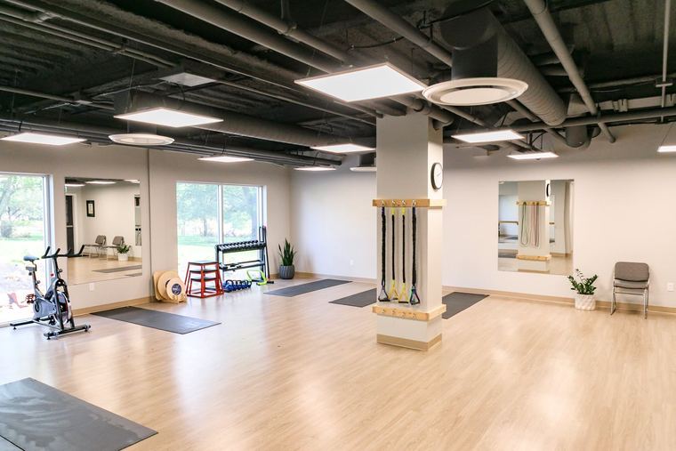 The main training floor with mirrors, spin bike, and free weights