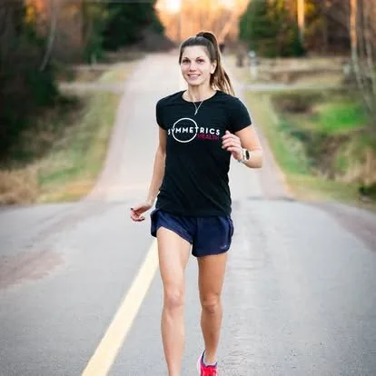 A runner in a Symmetrics Health shirt on a country road