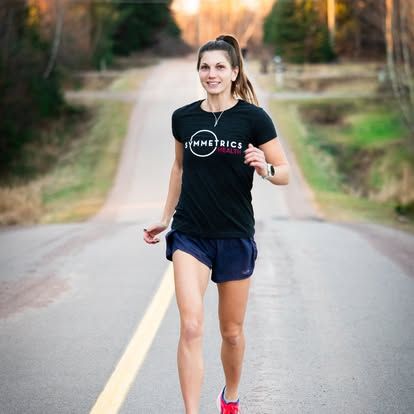 A runner in a Symmetrics Health shirt on a country road
